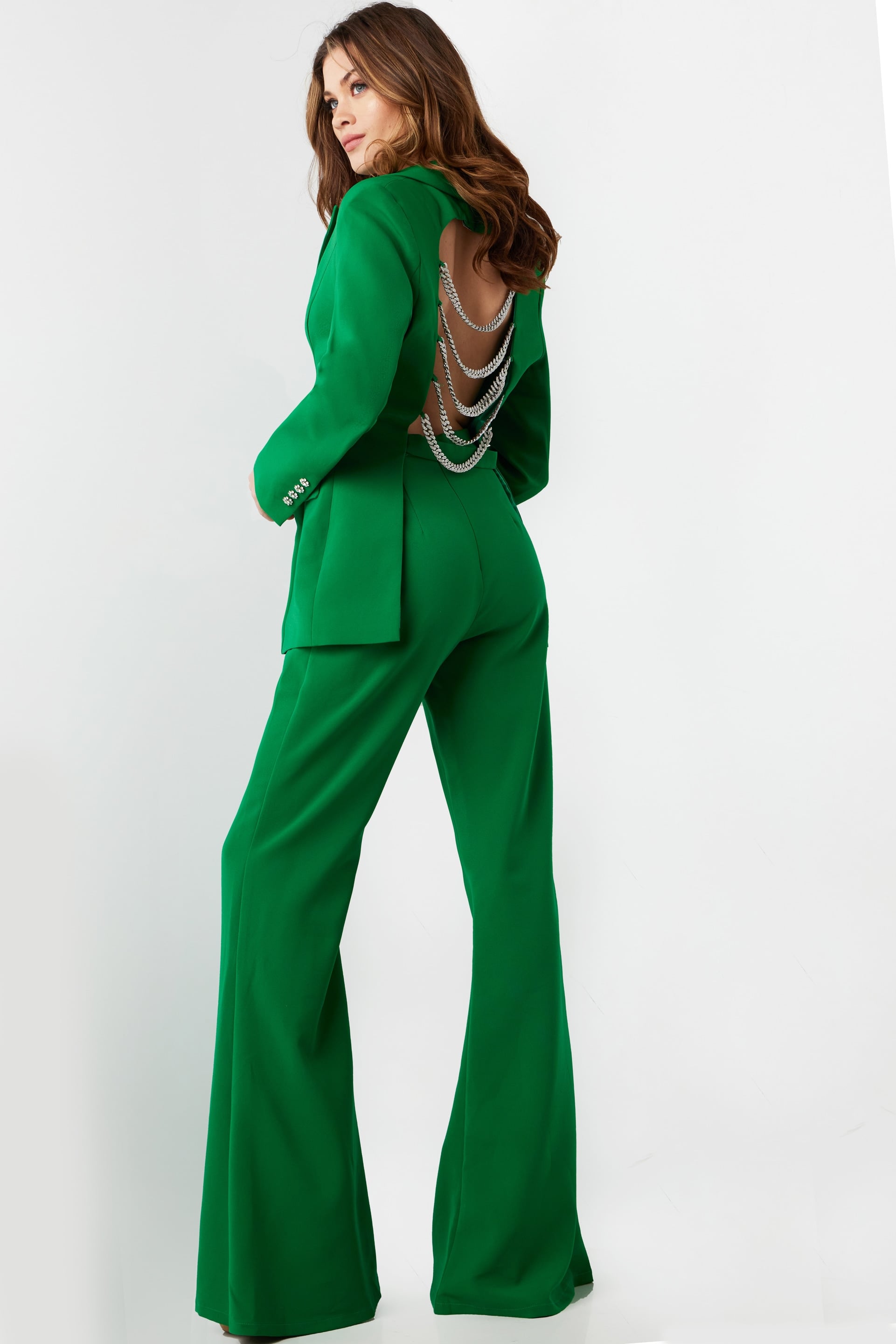 26144-EMERALD-92.jpg Model wearing Jovani 26144 green pantsuit with open back and chain detailing.
