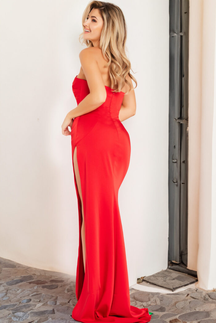 Model wearing Jovani 26166 red dress with high slit, back view.