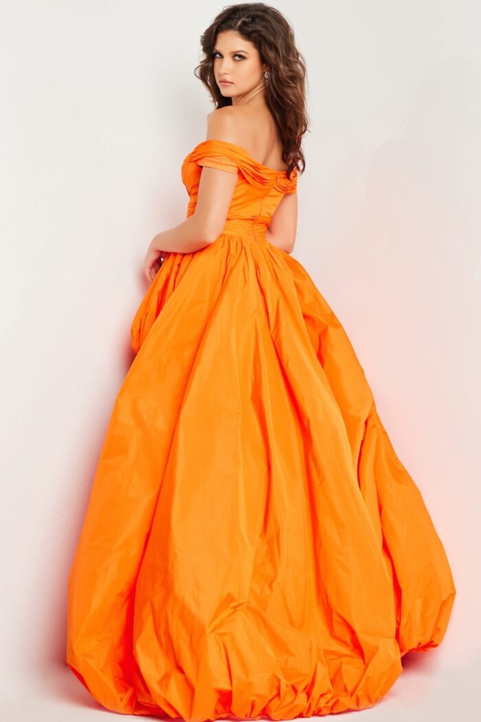 Model showing back view of Jovani 27804 orange dress with voluminous skirt and off-the-shoulder design.