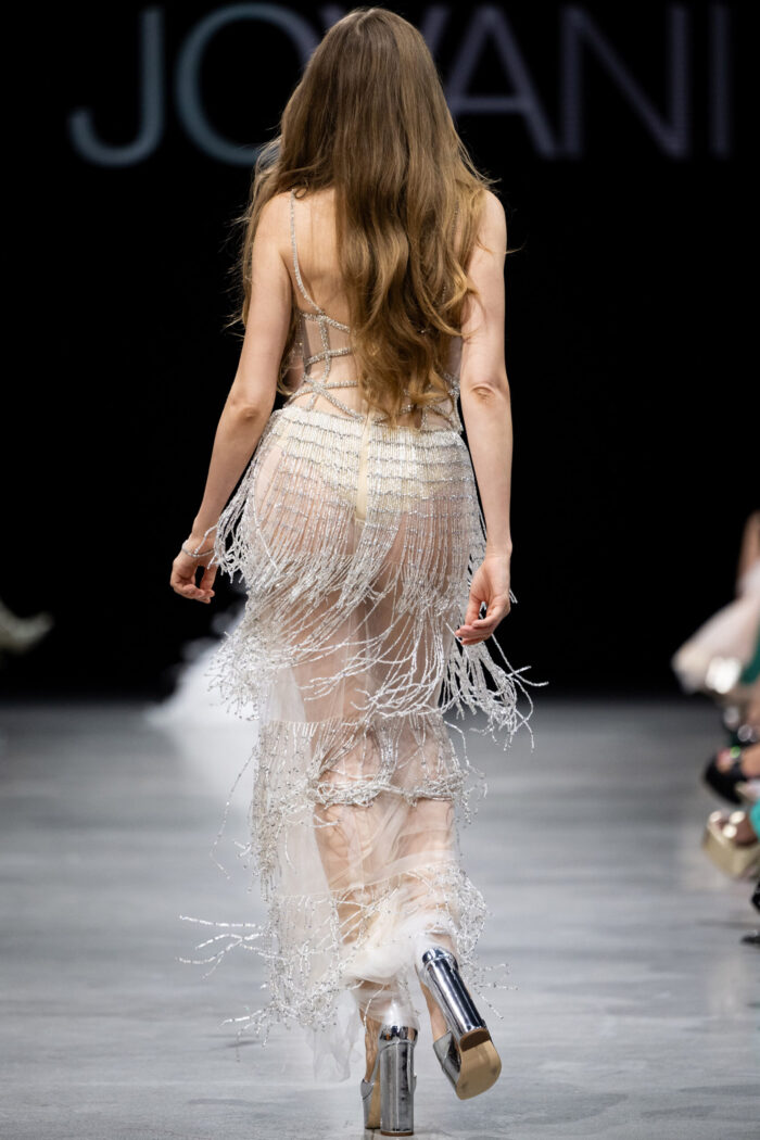 Model in Jovani 36423 nude dress with intricate back detailing.