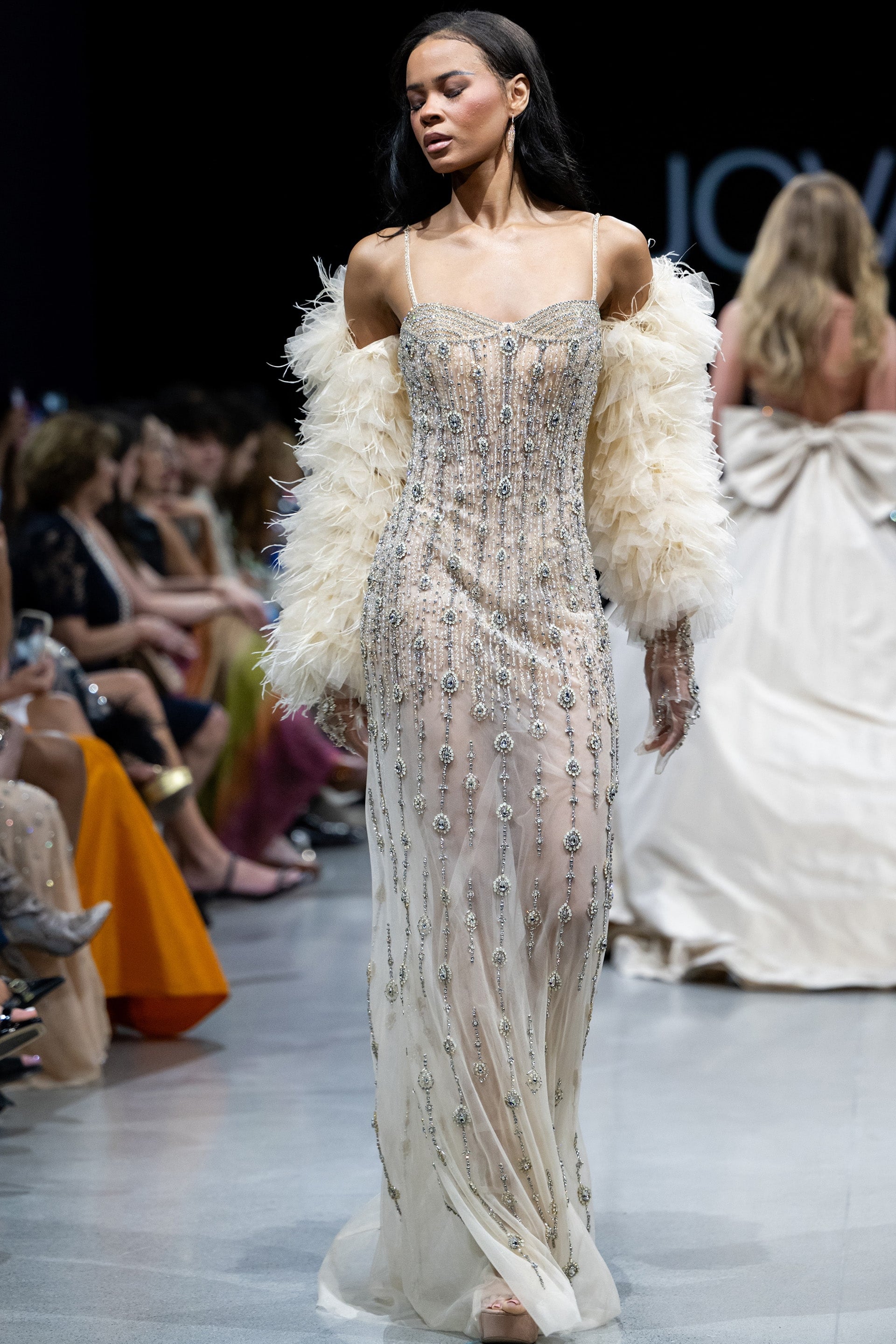 36510.jpg Model wearing Jovani 36510 nude dress with intricate beadwork and off-shoulder cape sleeves, showcasing front view.