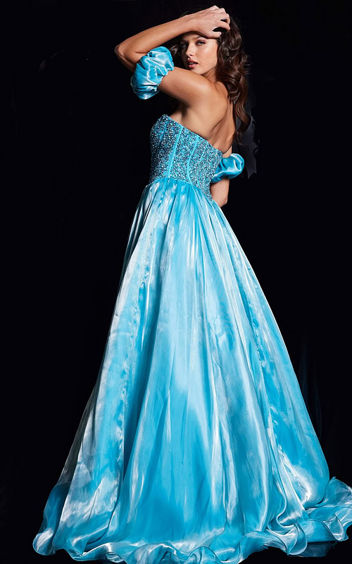 Model wearing Jovani 36591 blue ball gown showcasing the back with off-the-shoulder puff sleeves and flowing skirt.