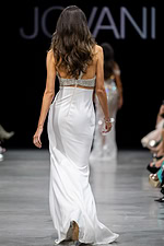 Model wearing Jovani 36857, white dress showing open back design with embellished halter straps.