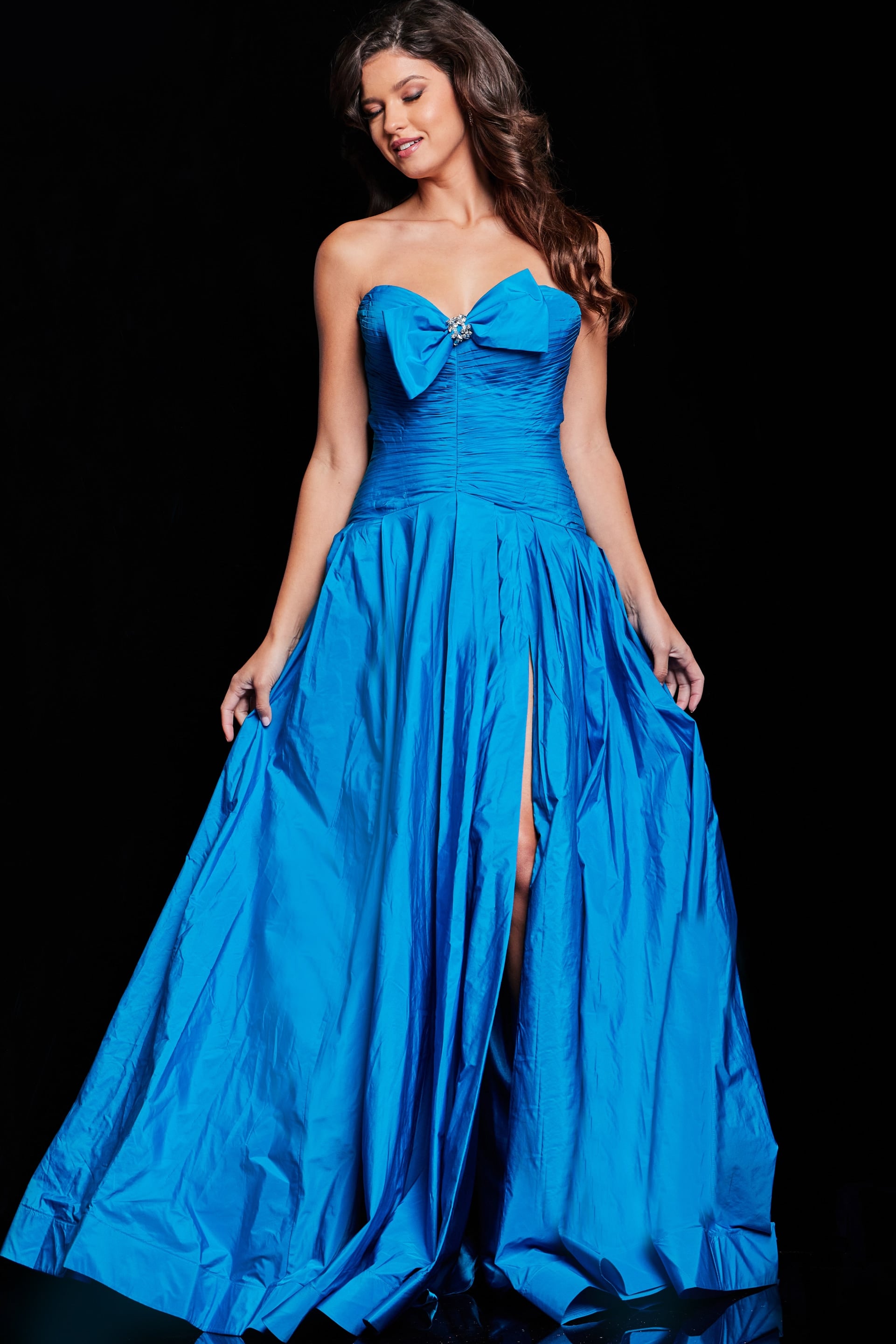 37066_PEACOCK_2045.jpg Model wearing Jovani 37066 blue gown with sweetheart neckline and bow detail, featuring a high slit.