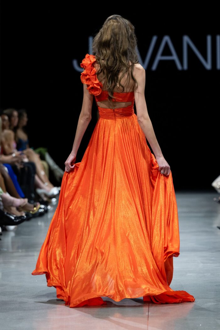 Back view of model wearing Jovani 37254 orange gown with one-shoulder floral applique.