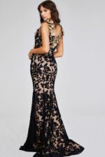 Model wearing Jovani 38497 black lace gown, back view showing open back design.