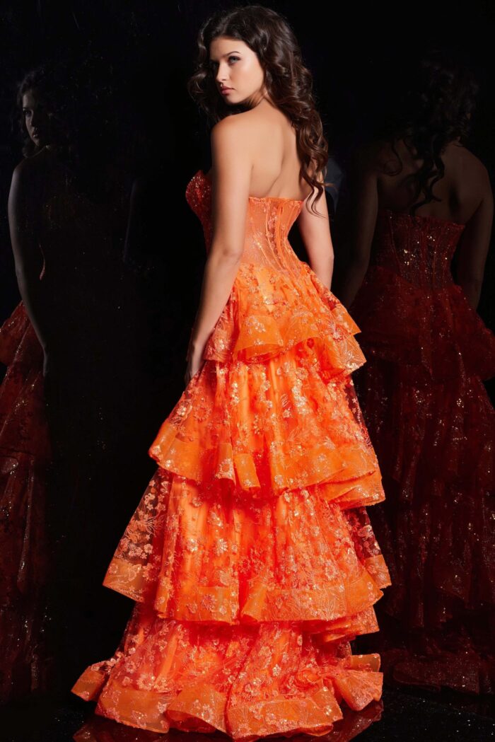 Back view of model in Jovani 38528 orange gown with layered skirt