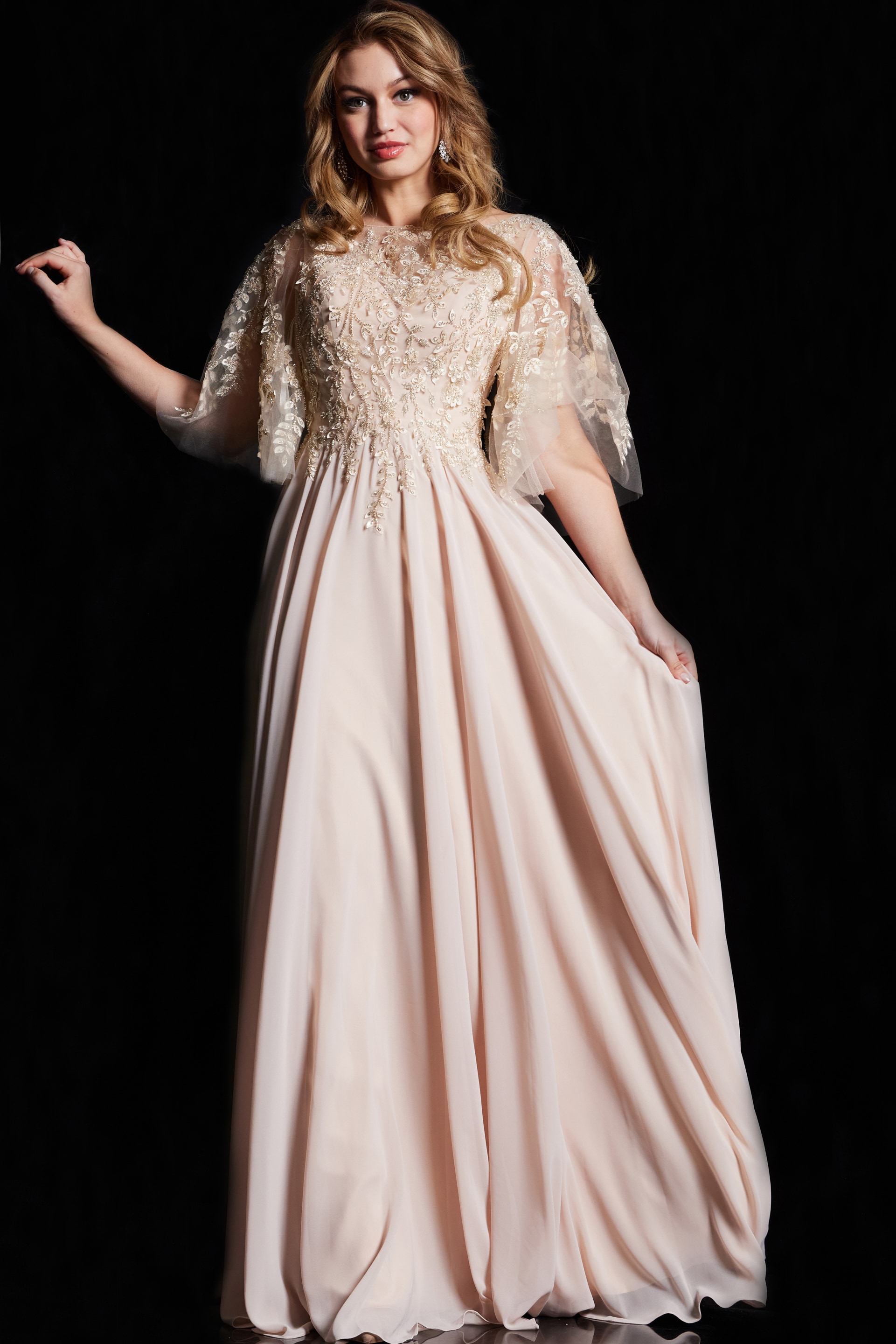 38622-CHAMPAGNE-9.jpg Model wearing Jovani 38622 beige gown with embroidered bodice and cape sleeves.