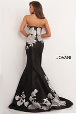 Model wearing Jovani 3917 black gown with silver floral embroidery from the back view.