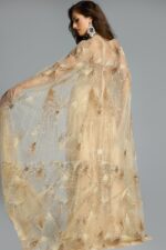 Back view of gold evening gown showcasing the sheer cape overlay with geometric beading and sparkle.