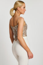Side angle of model in silver sequin corset top paired with high-waisted white pants.
