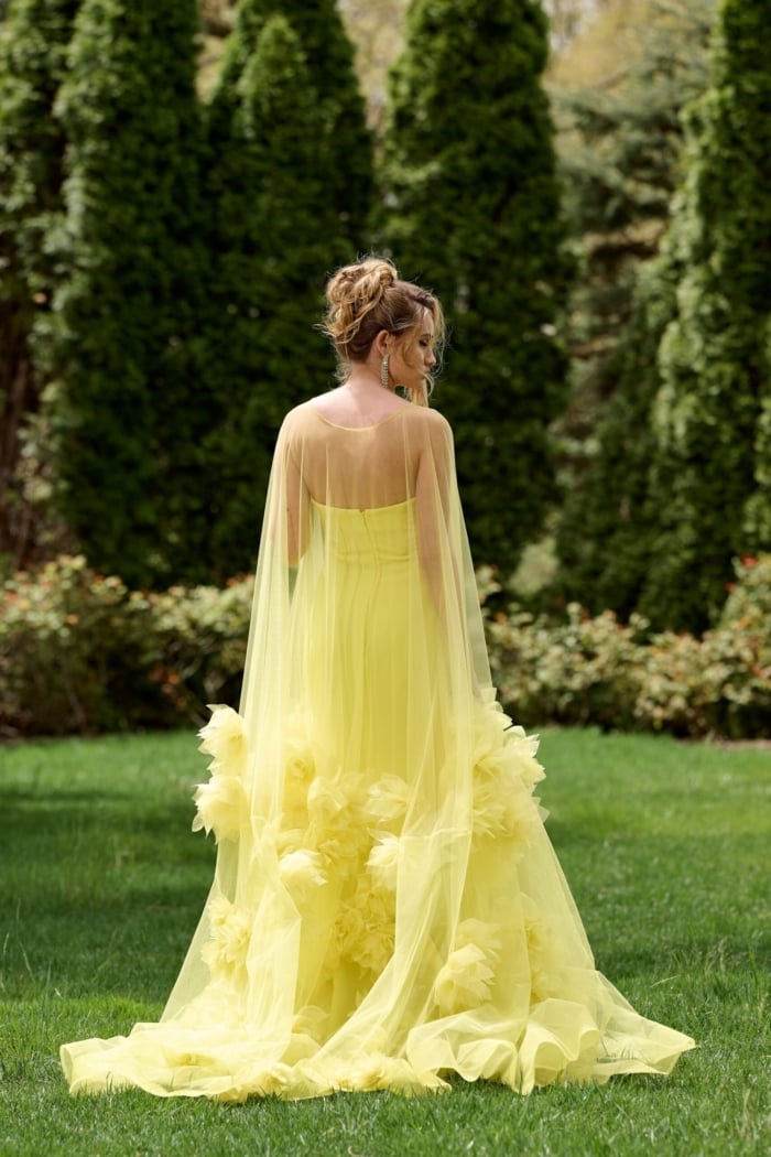 Model wearing Jovani 40092 yellow gown with floral appliqués, back view