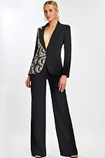 Model wearing black pantsuit with asymmetric sequin detailing and plunging neckline.