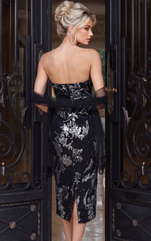 Back view of a black strapless embroidered sequin midi dress with a fitted silhouette, back slit, and sheer tulle wrap draped over the arms.