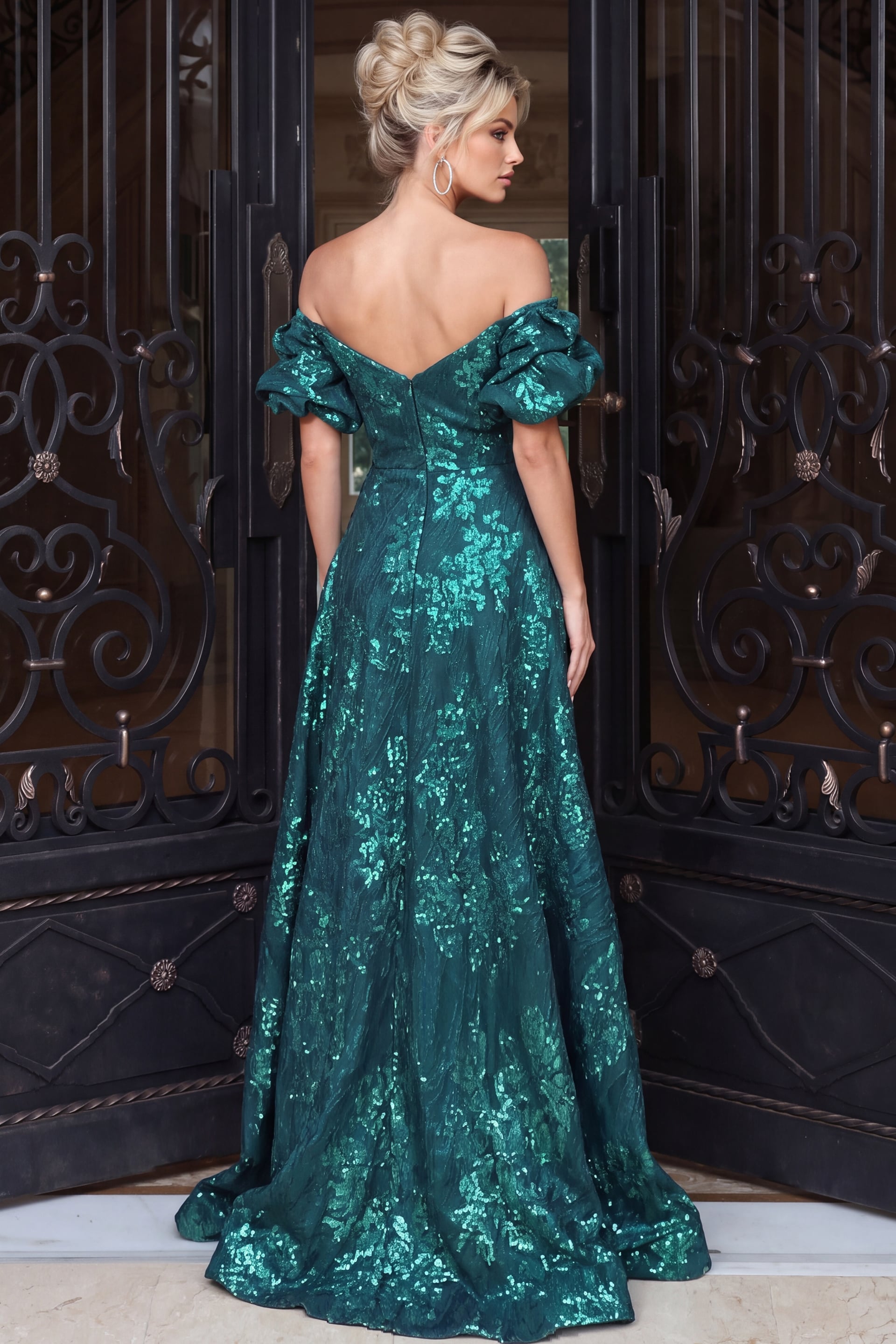 Back view of an emerald teal metallic jacquard gown with an off-the-shoulder V-back, puff sleeves, fitted bodice, and full-length skirt.