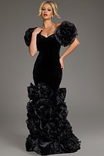Model wearing Jovani 40843 black velvet gown with dramatic ruffled hem and sculptural sleeves, full length front view.