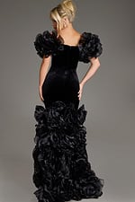 Back view of model in Jovani 40843 black velvet gown showcasing a fitted bodice and dramatic ruffles.
