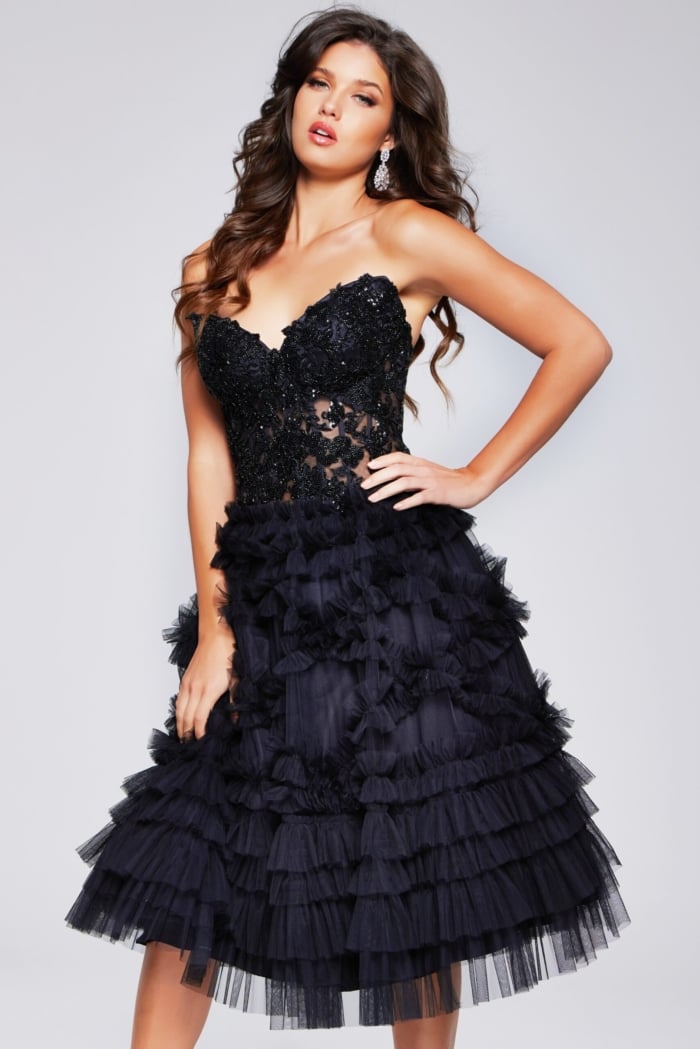 Model wearing Jovani 40854 black cocktail dress with lace applique bodice and ruffled skirt, front view.