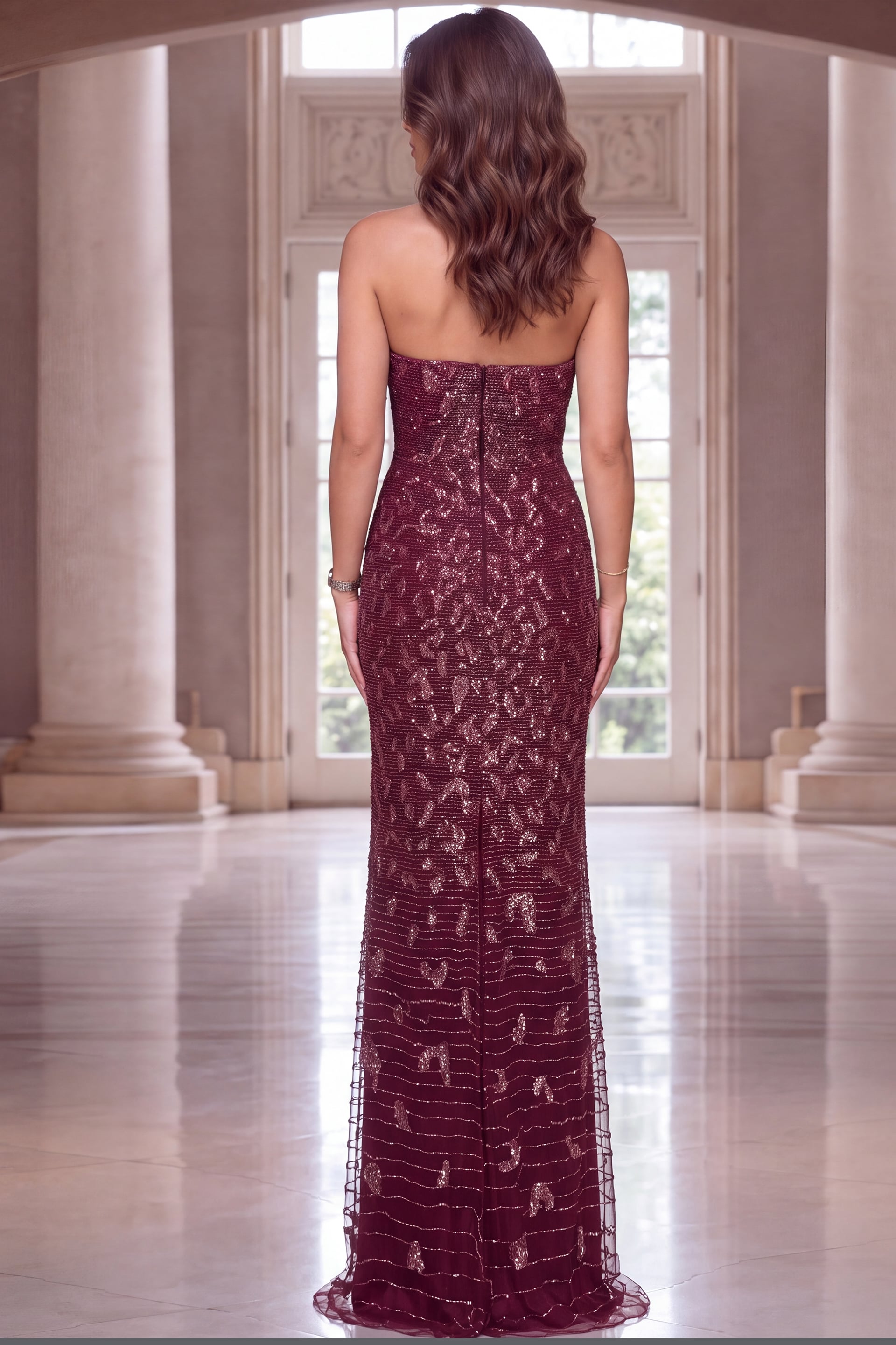 Wine beaded strapless gown seen from behind, fitted column shape with sweeping tulle hem