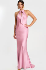 Woman wearing a mauve satin halter gown with a front bow tie and fit-and-flare silhouette.
