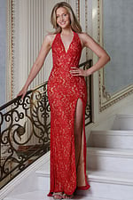 red halter plunge gown with lace overlay and high slit - front full body, smiling, hand on banister, high slit