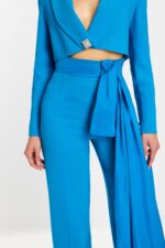 Close-up of rhinestone button and sash detail on high-waisted pantsuit