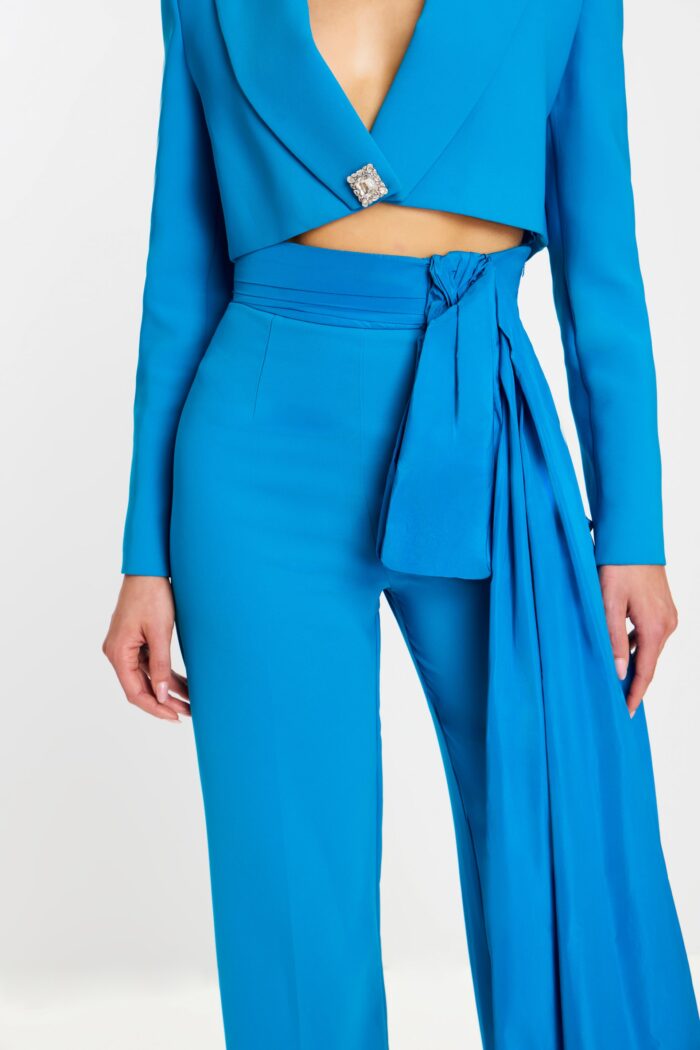 Close-up of rhinestone button and sash detail on high-waisted pantsuit