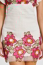 Close-up of skirt with bold pink and orange floral embroidery on white eyelet fabric
