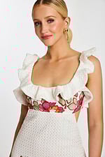 Bodice detail showing floral embroidery and ruffled neckline on white textured fabric