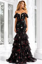 Black off-the-shoulder evening gown with floral embroidery, sheer ruffle sleeves, and a dramatic tiered tulle mermaid skirt.