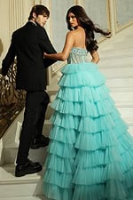 Model posing on staircase in ruffled tulle gown with elegant train