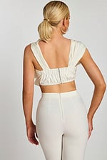 Back view of cropped top with wide straps and exposed zipper detail, paired with fitted pants