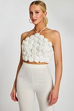 Woman wearing white 3D rosette halter crop top and high-waisted pants