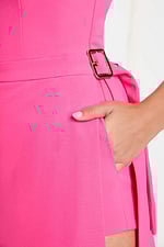Detailed close-up of gold buckle, waistline, and hand-in-pocket design on hot pink romper.