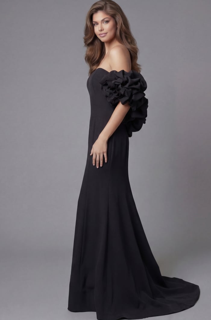 Side profile of Jovani 45653 black off-the-shoulder mermaid gown highlighting the dramatic rosette ruffle sleeve detail, clean bodice, and flowing train.