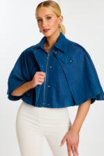Model Unzipping Cropped Denim Cape to Show Inner Placket and Hardware Details