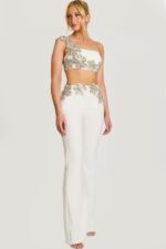 Close-up of beaded floral crop top with asymmetrical strap on ivory pantsuit