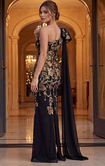 back view of black floral applique one shoulder gown with draped cape