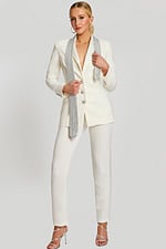 Front view of tailored white pantsuit with rhinestone tie and crystal buttons