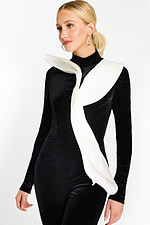 Close-up of white asymmetric ruffle over black velvet jumpsuit bodice