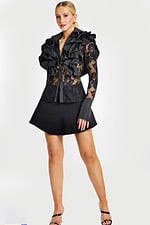 Woman wearing sheer black lace blouse with layered ruffle collar and flared black mini skirt