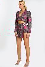 Side angle of cropped tweed jacket and belted mini skirt with metallic buckle