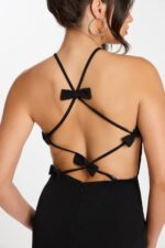 Close-up of strappy open back on black jumpsuit with multiple bows