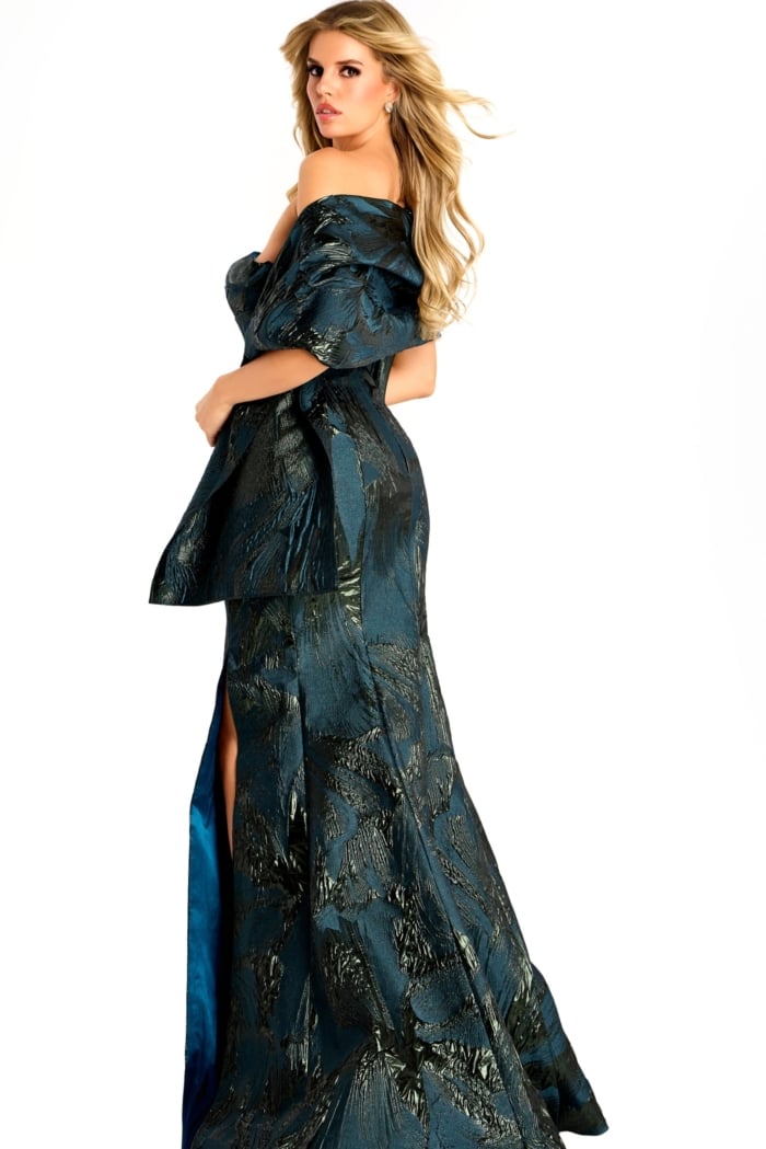 Off-shoulder metallic jacquard gown with structured draped sleeves, fitted bodice, and a floor-length slit skirt.
