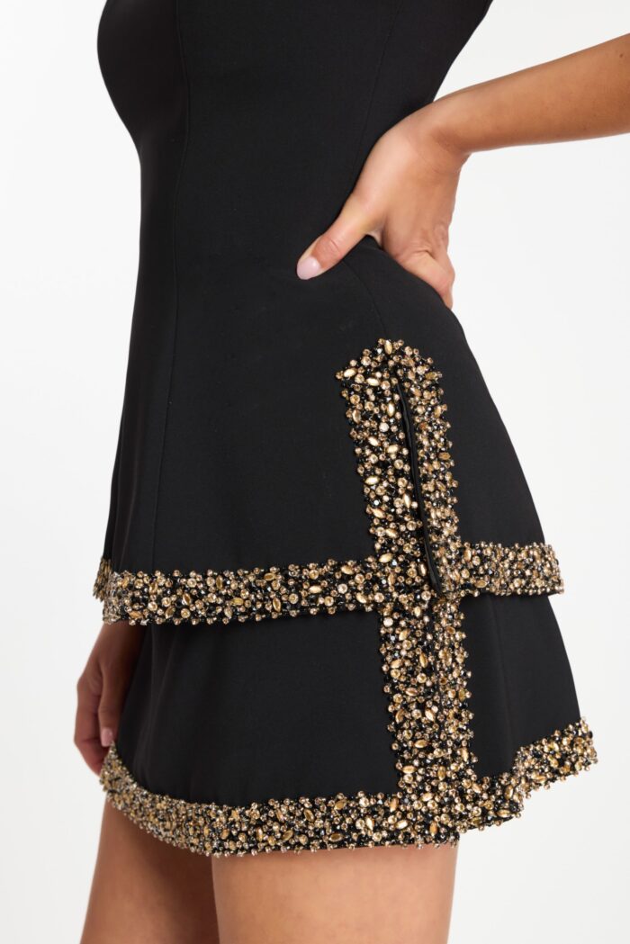 Detailed side view of gold and black beaded pocket trim on mini dress
