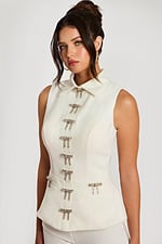 Three-quarter front view of ivory pant suit with crystal bow accents and collar