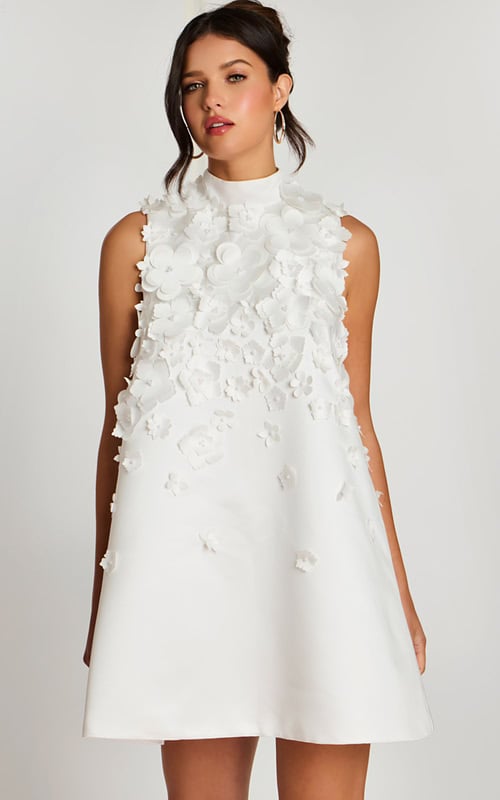 Close-up of high neckline and layered flower details on white satin dress