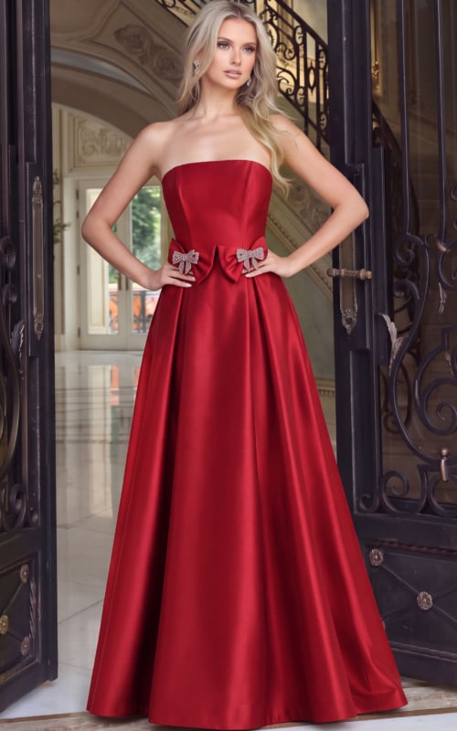 Close front view of red satin ball gown showing the crystal bow detail and pleated skirt