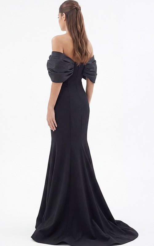 Black off-the-shoulder mermaid evening gown with dramatic puff sleeves and flowing train, model holding skirt.