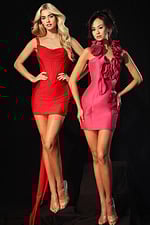 Two models wearing fitted designer dresses, one in a draped red mini with a bow train and the other in a pink dress with sculpted floral neckline details.